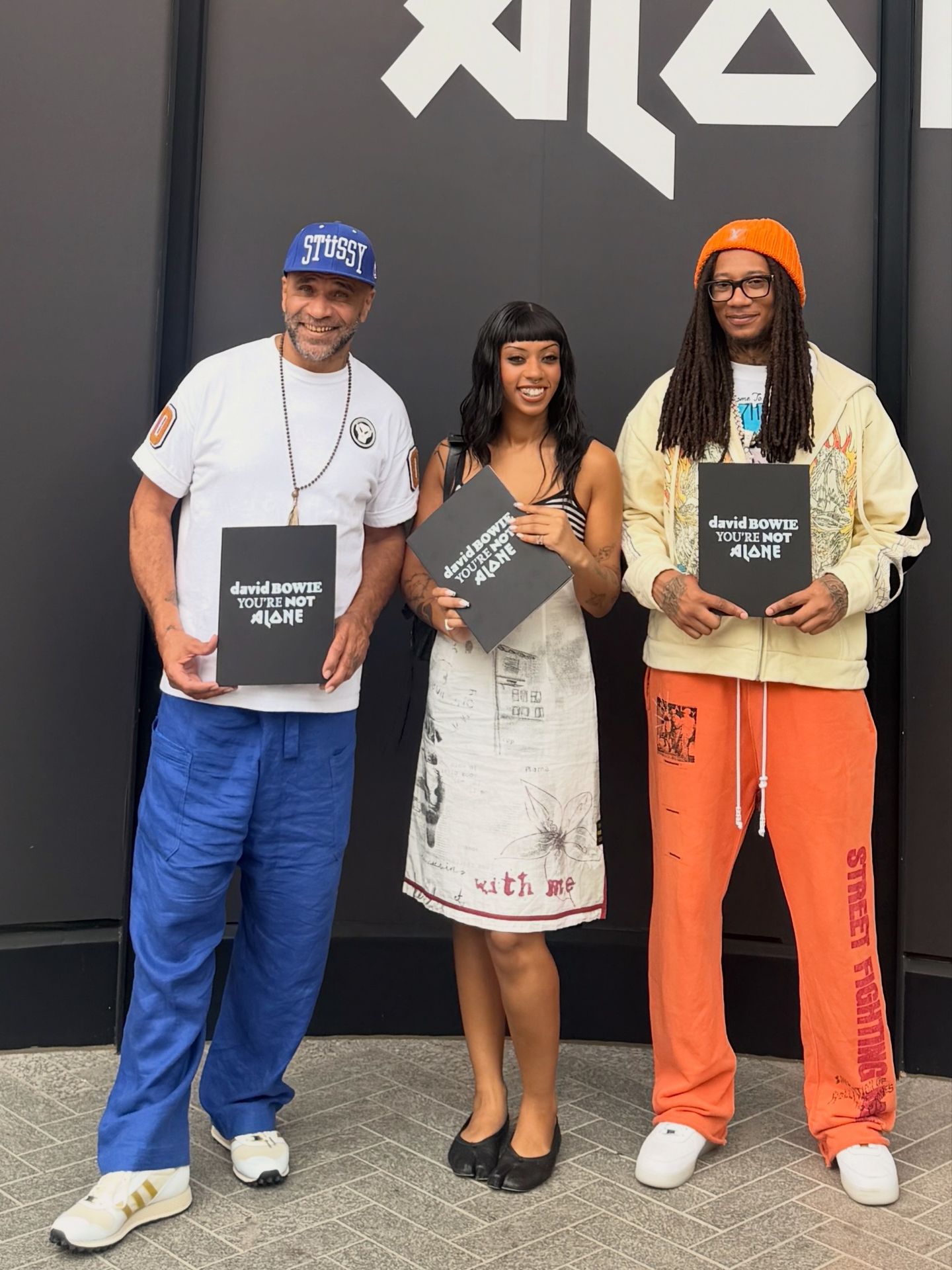 Three people holding David Bowie You’re Not Alone booklets
