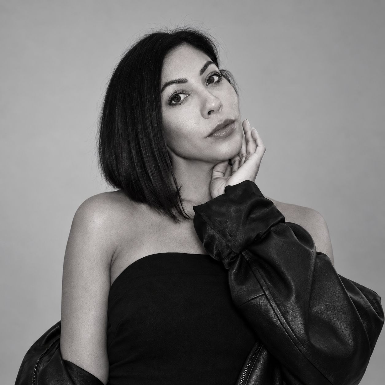 Black-and-white portrait of Heidi Jacob with a leather jacket and her hand beside her face