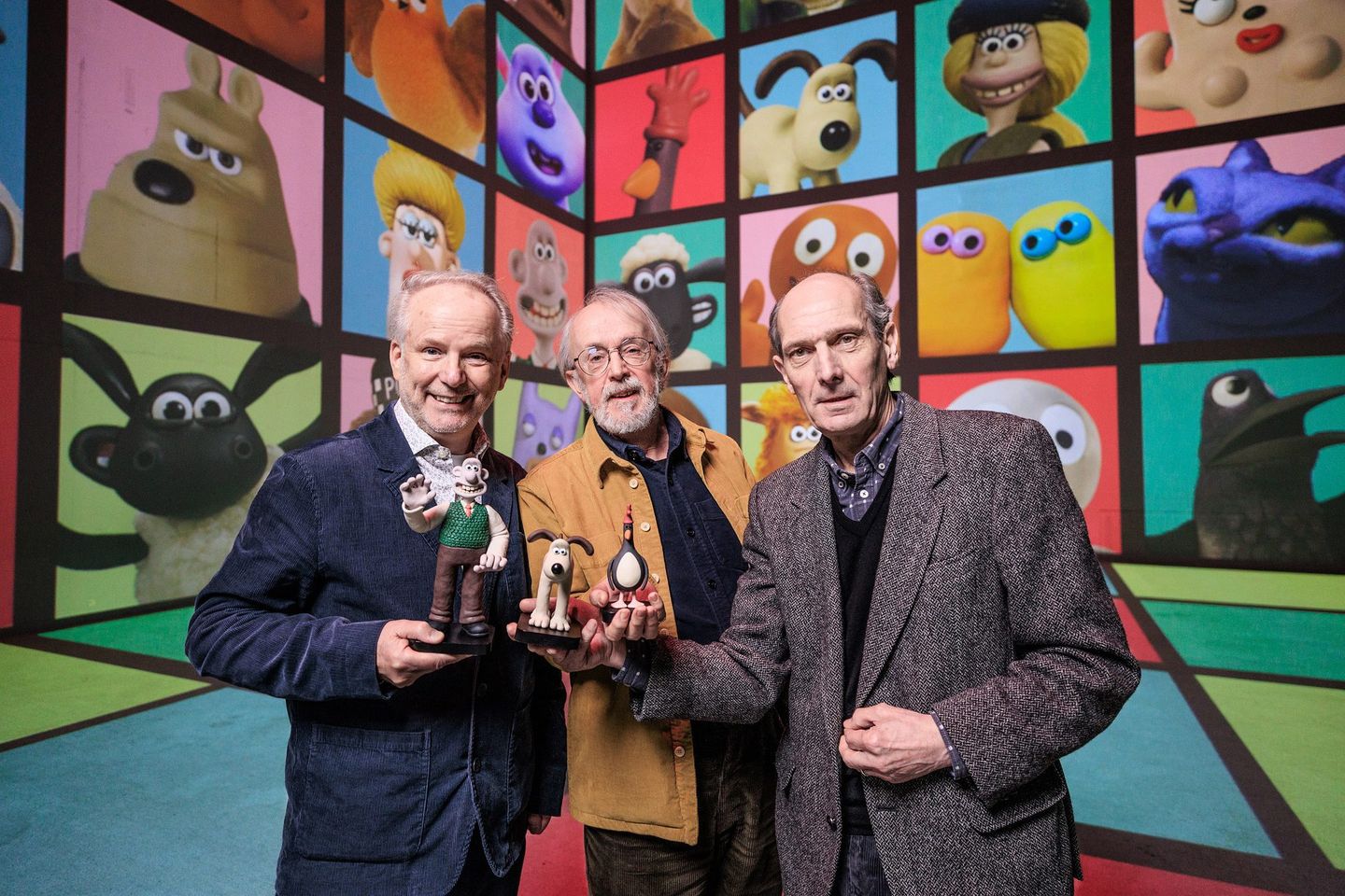 Aardman’s creators with Wallace and Gromit models in front of projected characters at The Lightroom