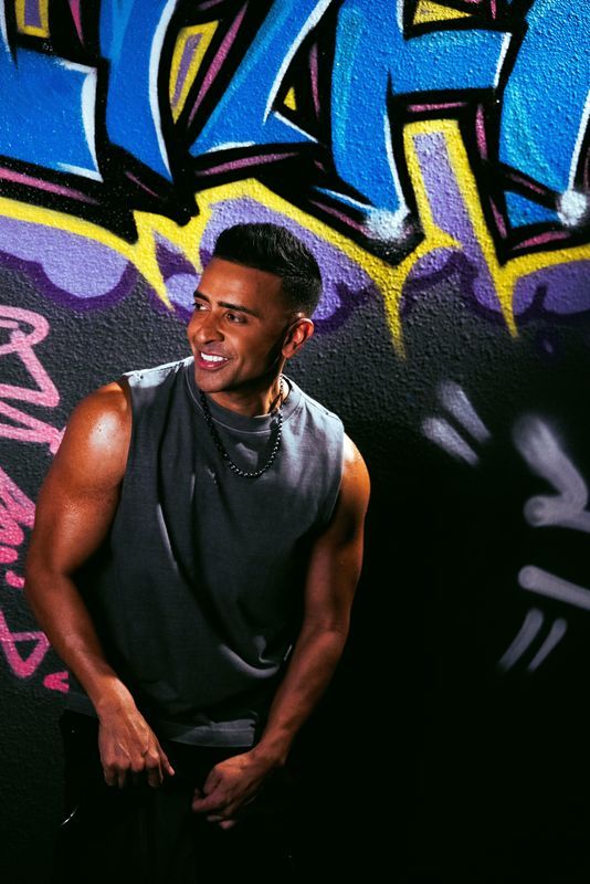Jay Sean smiling against a colourful graffiti wall